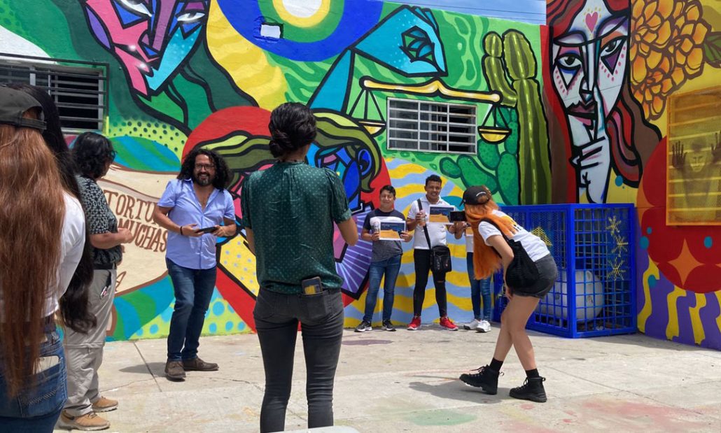 Jovenes posando frente a un mural muy colorido