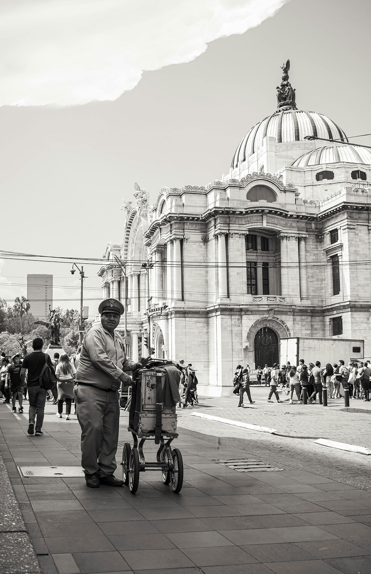 En la imagen en blanco y negro, un organillero posa al frente del palacio de bellas artes