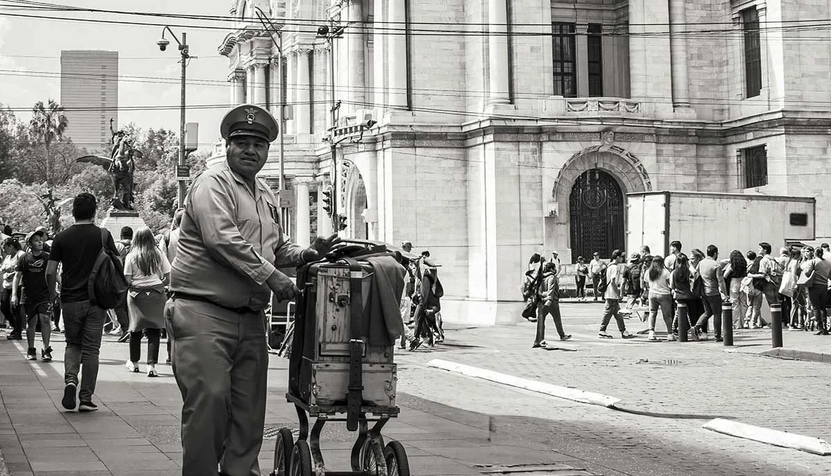 En la imagen un organillero típico de la CDMX posa frente al palacio de Bellas artes